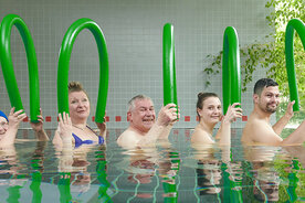 Mehrere Menschen mit Poolnudeln im Schwimmbad