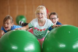 Kinder auf grünen Gymnastikbällen